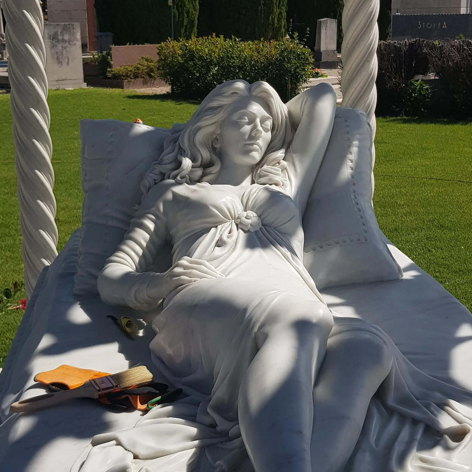 Una figura distesa in marmo posata in un giardino