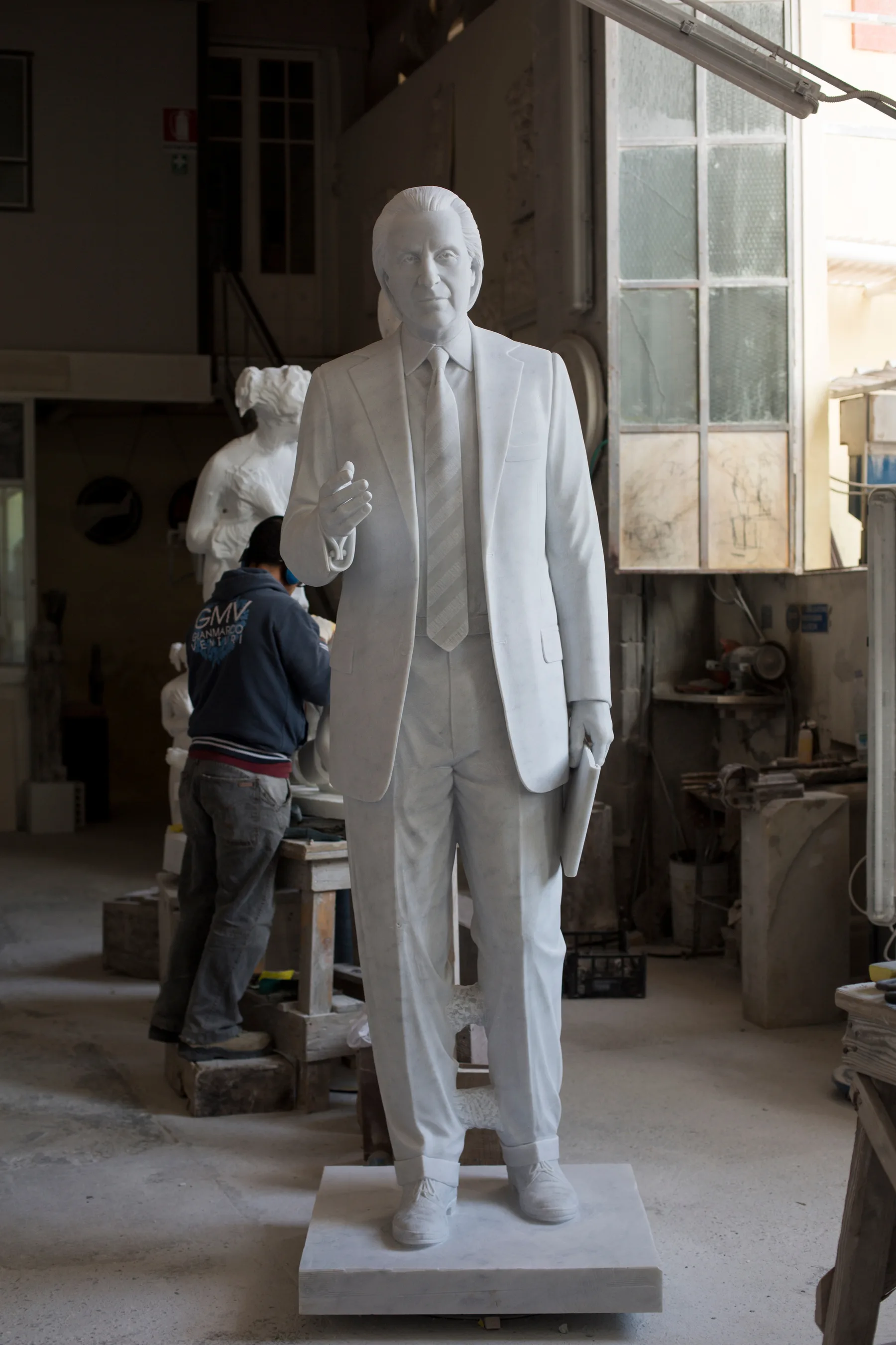 Uno scultore rifinisce a mano una statua in piedi