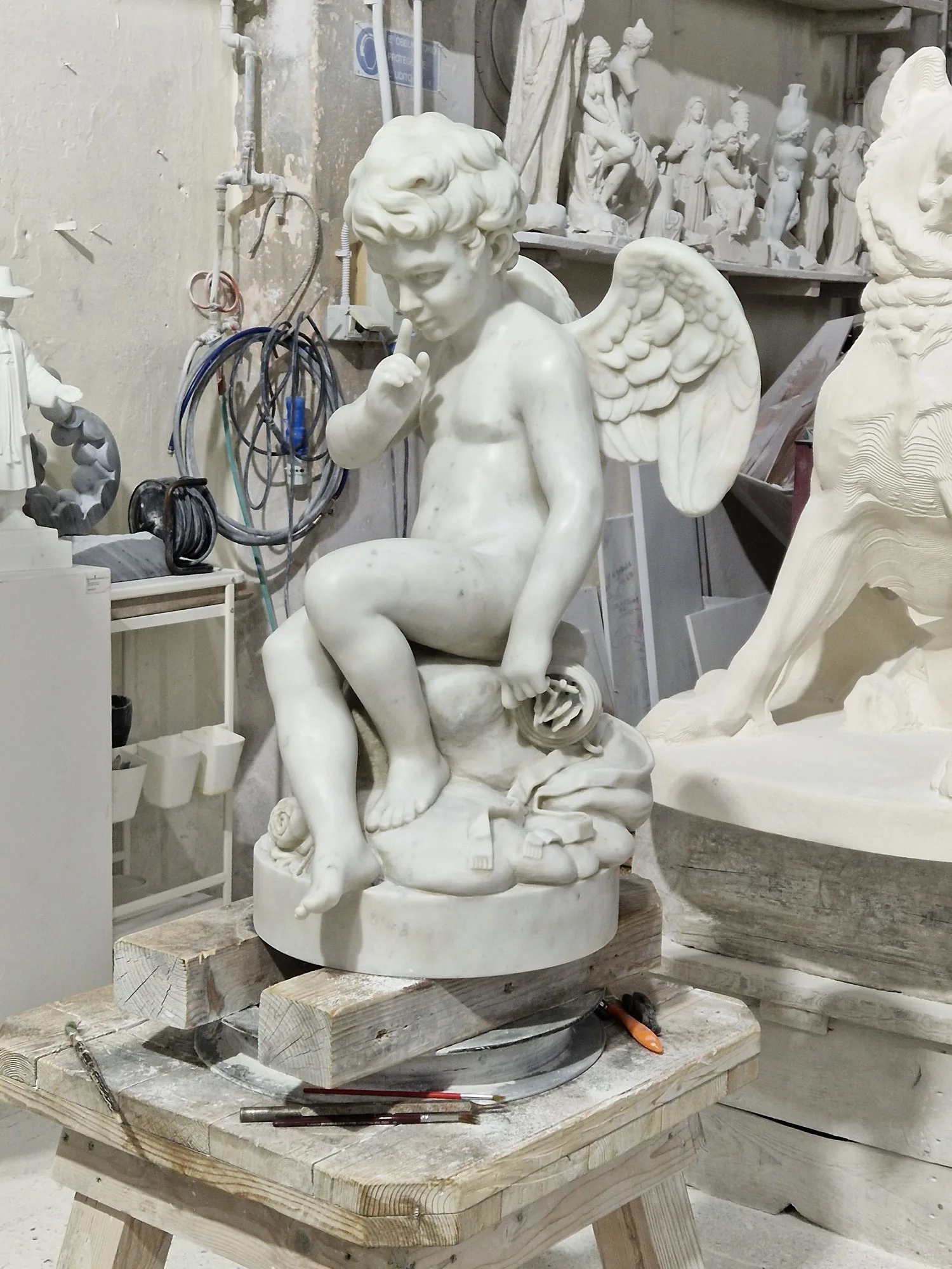 Un putto alato sul banco di lavoro, tra cavi e strumenti